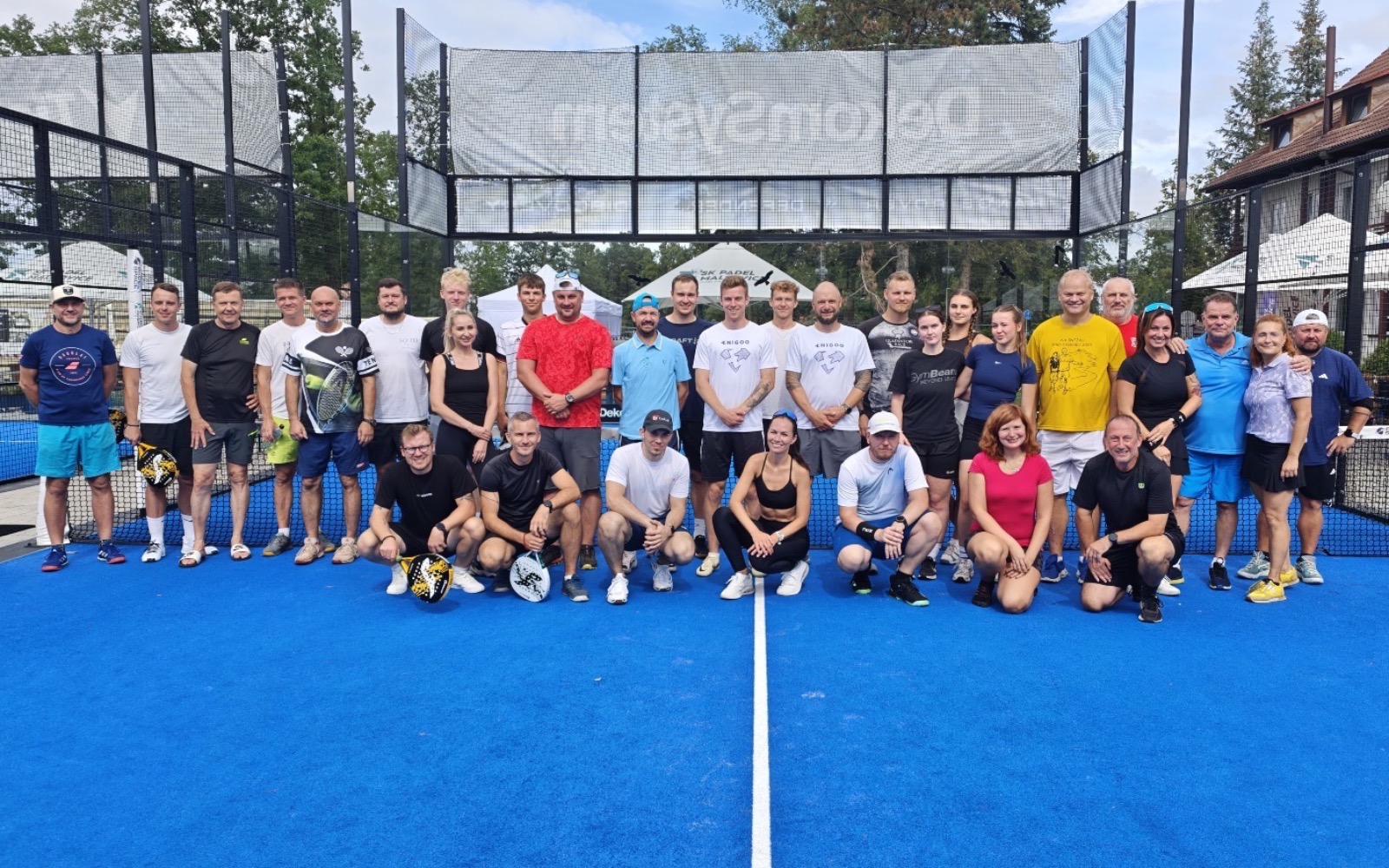 Společná fotografie účastníků partnerského turnaje Mountfieldu HK na kurtu SK Padel Malšovice.